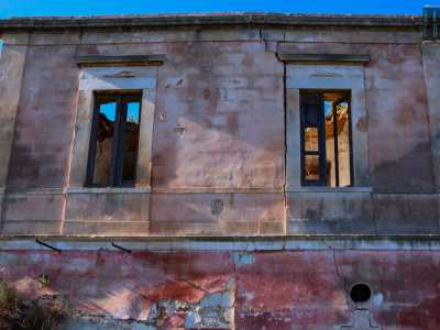 ...senza finestre e dalle pareti scrostate che lasciano intravedere il color rosso che ricopriva i muri